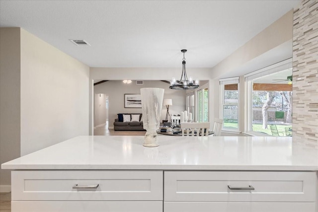 kitchen featuring light hardwood / wood-style floors, hanging light fixtures, white cabinetry, and ceiling fan with notable chandelier