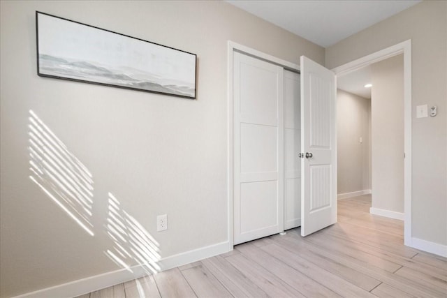 unfurnished bedroom with light wood-type flooring and a closet