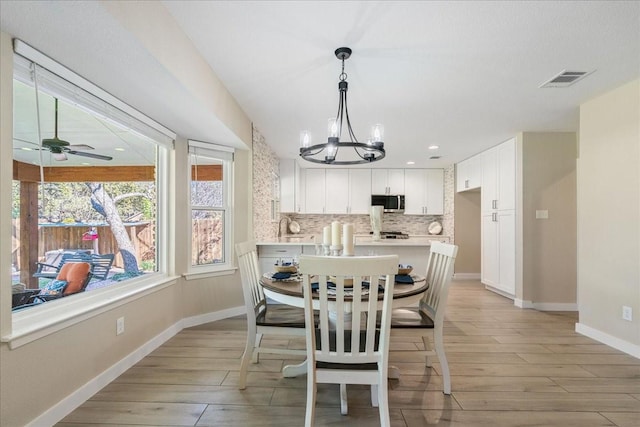 dining space with light hardwood / wood-style flooring and ceiling fan with notable chandelier