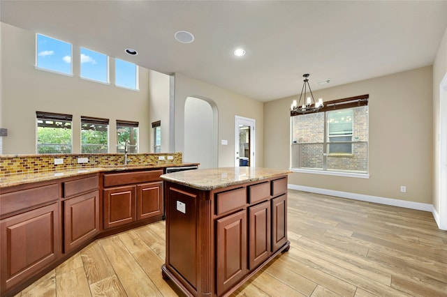 kitchen with a kitchen island, a chandelier, pendant lighting, and light hardwood / wood-style floors