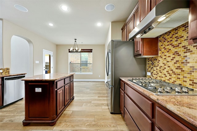 kitchen with light hardwood / wood-style floors, stainless steel appliances, light stone countertops, pendant lighting, and an inviting chandelier