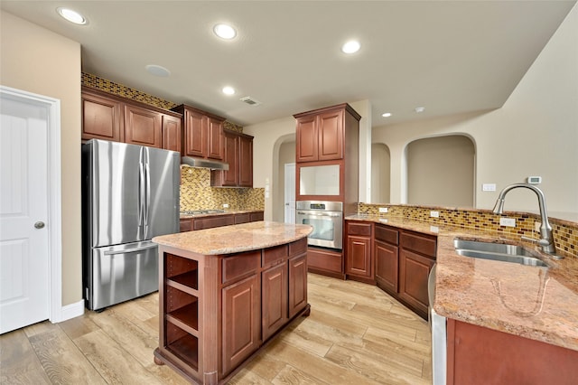 kitchen with stainless steel appliances, a center island, light wood-type flooring, and sink