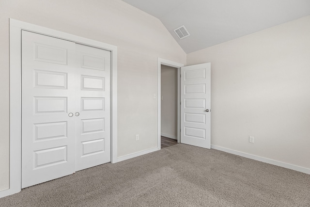 unfurnished bedroom featuring vaulted ceiling, a closet, and carpet