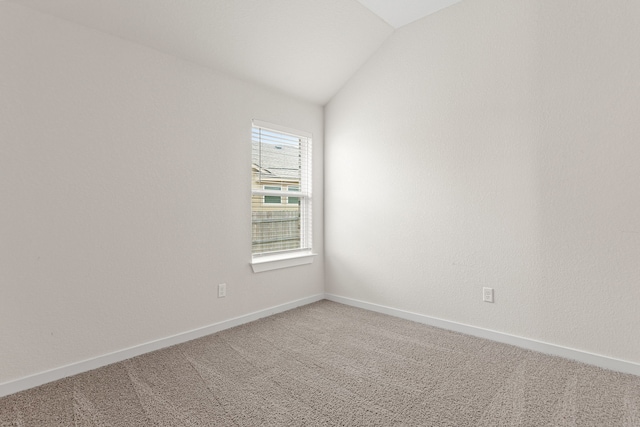 empty room featuring vaulted ceiling and carpet flooring