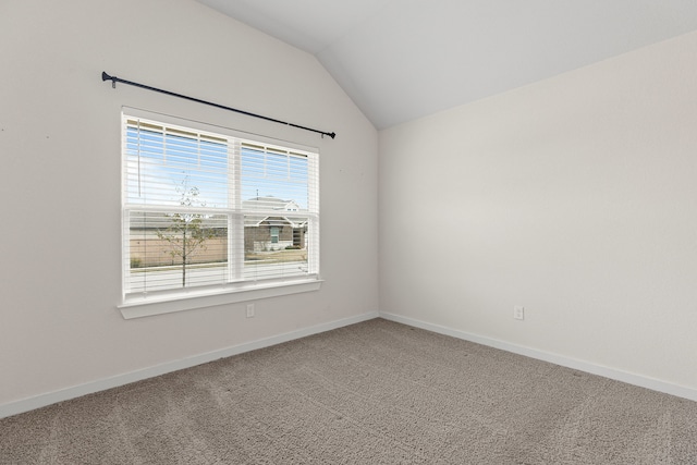 carpeted empty room featuring vaulted ceiling