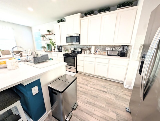 kitchen featuring stainless steel appliances, white cabinetry, and backsplash