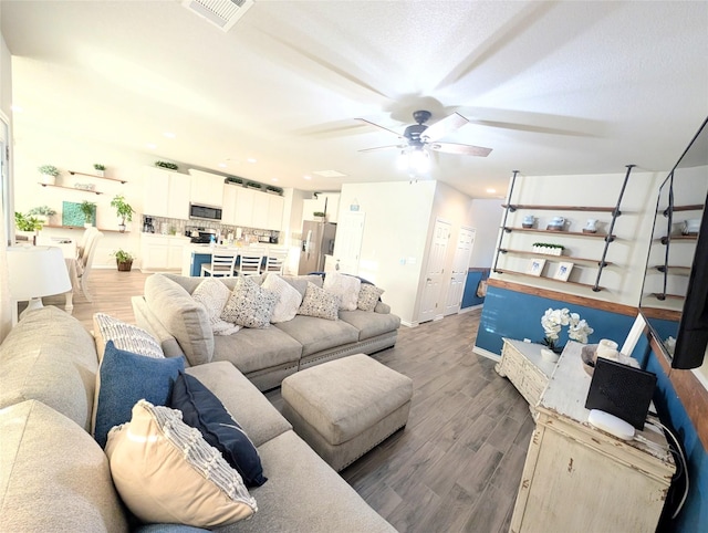 living room with ceiling fan and dark wood-type flooring