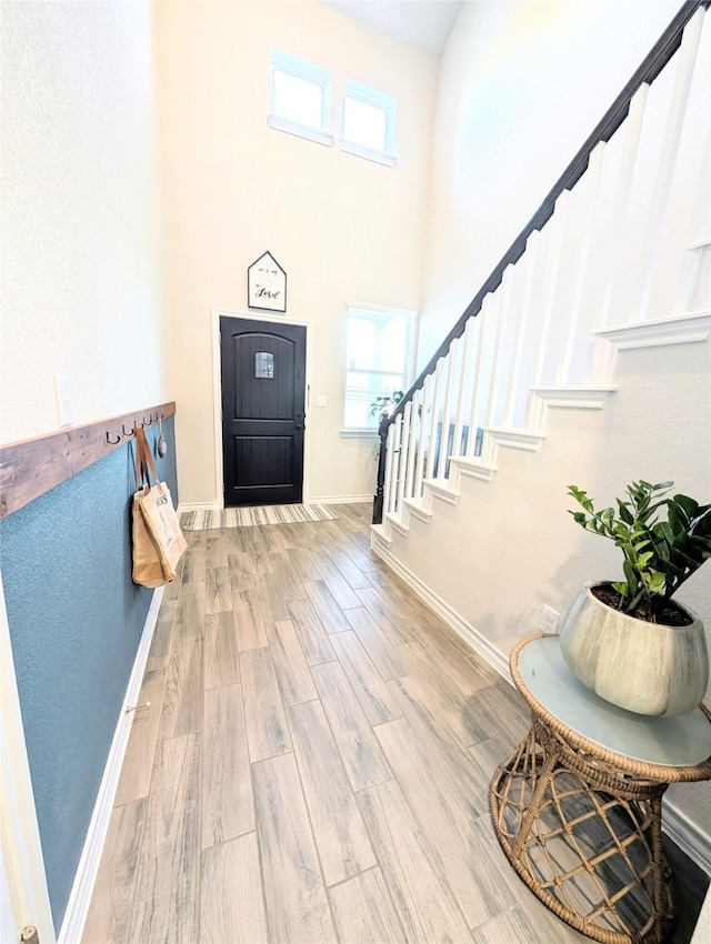 entrance foyer featuring a healthy amount of sunlight, a towering ceiling, and hardwood / wood-style flooring