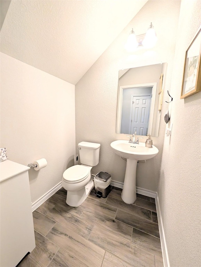 bathroom with toilet and lofted ceiling