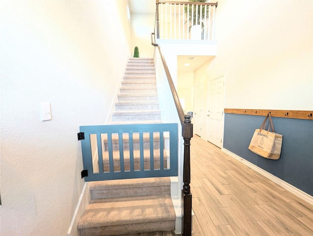 staircase with a towering ceiling and wood-type flooring