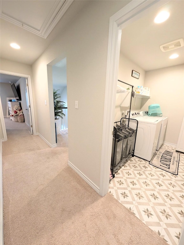 hallway with independent washer and dryer, light colored carpet, and ornamental molding