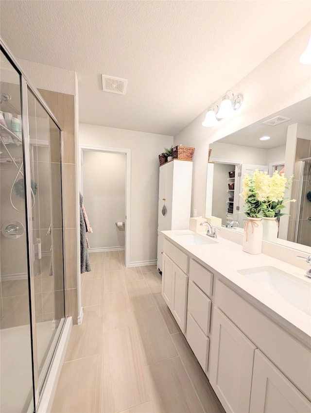 bathroom with vanity, a textured ceiling, and walk in shower