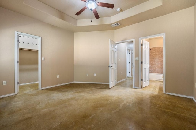 unfurnished bedroom featuring ensuite bath, ceiling fan, and a tray ceiling