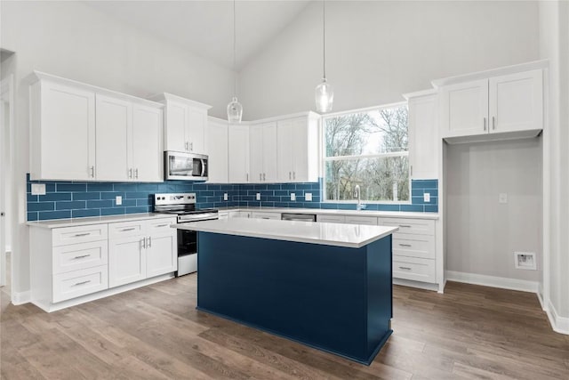 kitchen with white cabinetry, stainless steel appliances, a kitchen island, and pendant lighting