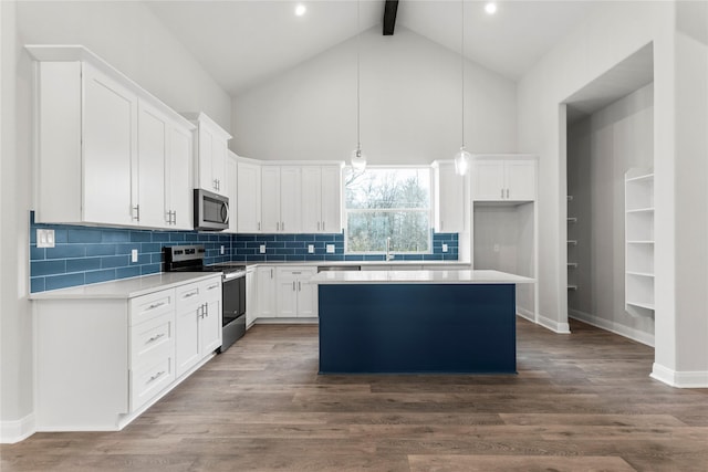 kitchen with appliances with stainless steel finishes, a center island, pendant lighting, high vaulted ceiling, and white cabinets