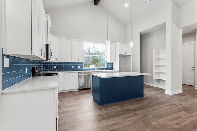 kitchen with white cabinets, a center island, beamed ceiling, high vaulted ceiling, and appliances with stainless steel finishes