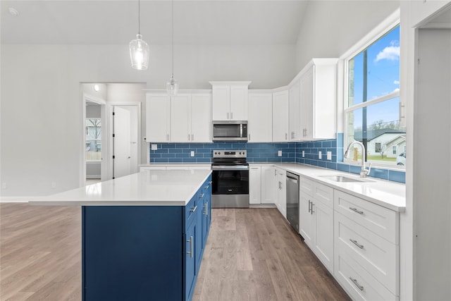 kitchen with stainless steel appliances, a center island, sink, white cabinetry, and blue cabinets