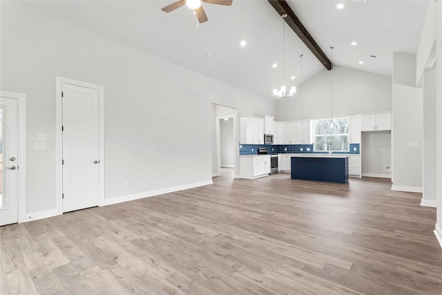 unfurnished living room featuring ceiling fan with notable chandelier, high vaulted ceiling, beamed ceiling, and light hardwood / wood-style flooring