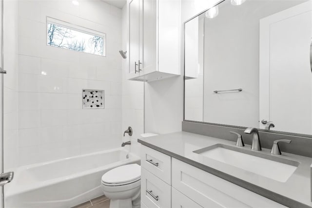 full bathroom featuring tiled shower / bath, vanity, and toilet