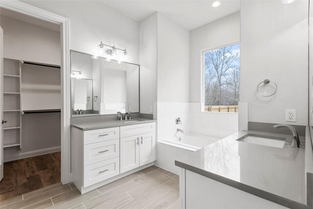 bathroom featuring a relaxing tiled tub and vanity