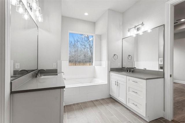 bathroom featuring tiled tub and vanity