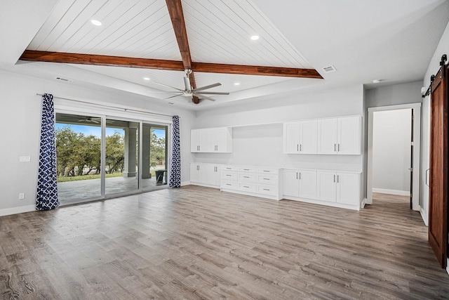 unfurnished living room featuring lofted ceiling with beams, wood ceiling, light wood-type flooring, a barn door, and ceiling fan