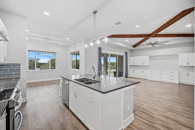 kitchen with a kitchen island with sink, appliances with stainless steel finishes, beamed ceiling, sink, and white cabinetry