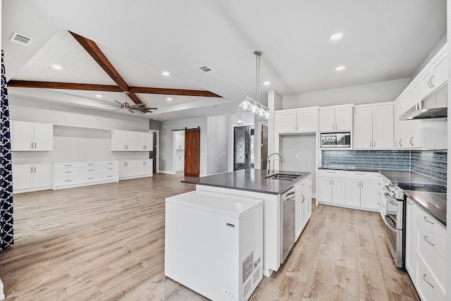 kitchen featuring an island with sink, appliances with stainless steel finishes, a barn door, and white cabinets