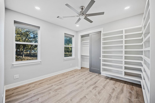 unfurnished bedroom with light wood-type flooring, ceiling fan, a closet, and multiple windows