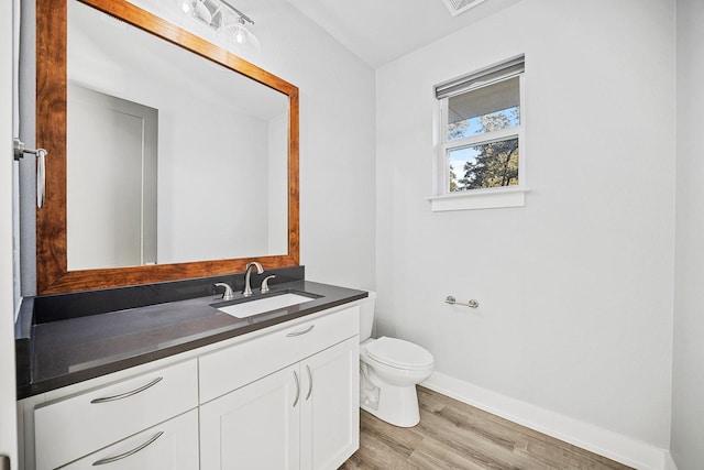 bathroom featuring toilet, vanity, and hardwood / wood-style flooring