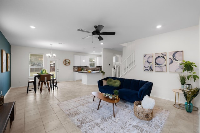 living room with ceiling fan with notable chandelier and light tile patterned floors