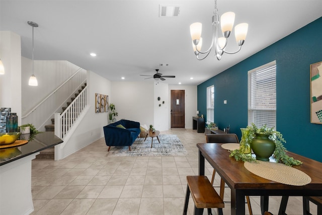 tiled dining space featuring ceiling fan with notable chandelier