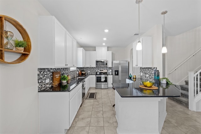 kitchen with hanging light fixtures, light tile patterned floors, white cabinetry, appliances with stainless steel finishes, and sink