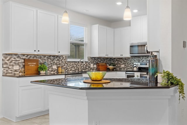 kitchen with decorative backsplash, white cabinetry, hanging light fixtures, and appliances with stainless steel finishes