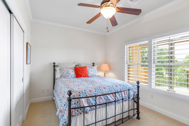 carpeted bedroom featuring ceiling fan, a closet, and crown molding