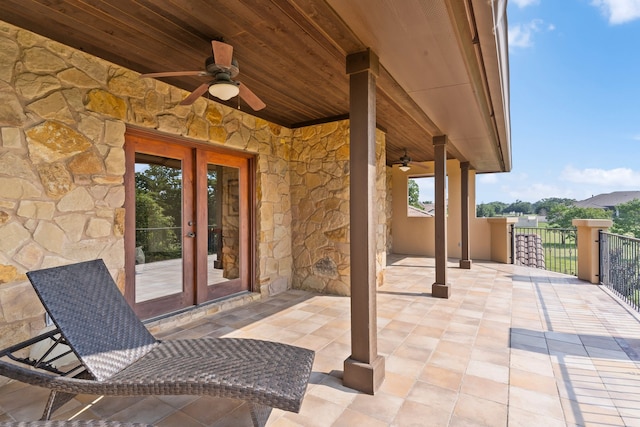 view of patio with french doors, ceiling fan, and a balcony