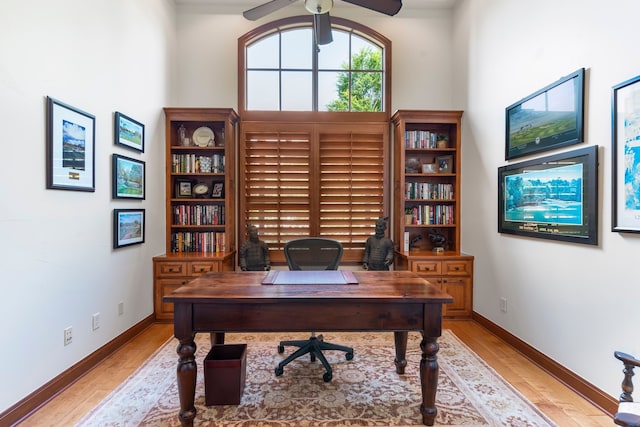 office featuring ceiling fan, light hardwood / wood-style flooring, and a towering ceiling