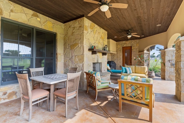 view of patio / terrace with ceiling fan and an outdoor living space with a fireplace