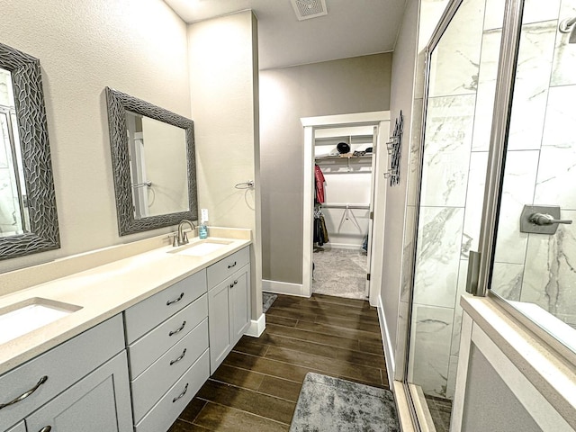 bathroom featuring a shower with door and vanity