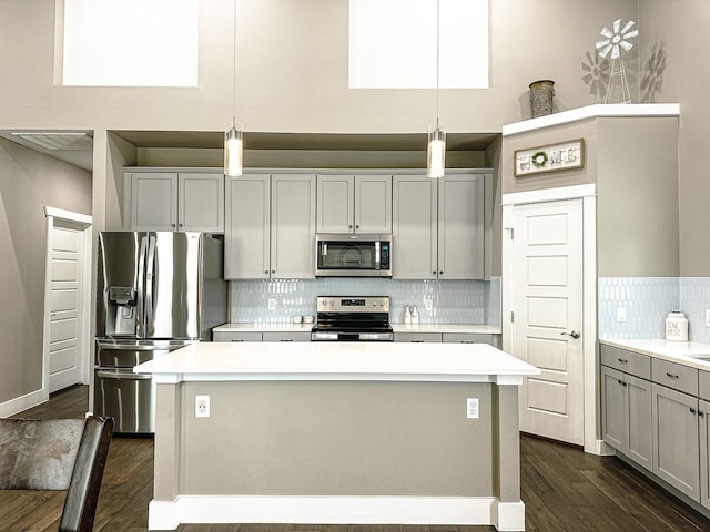 kitchen with a center island, backsplash, gray cabinets, pendant lighting, and appliances with stainless steel finishes