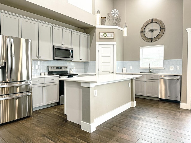 kitchen featuring pendant lighting, a center island, dark hardwood / wood-style flooring, appliances with stainless steel finishes, and sink