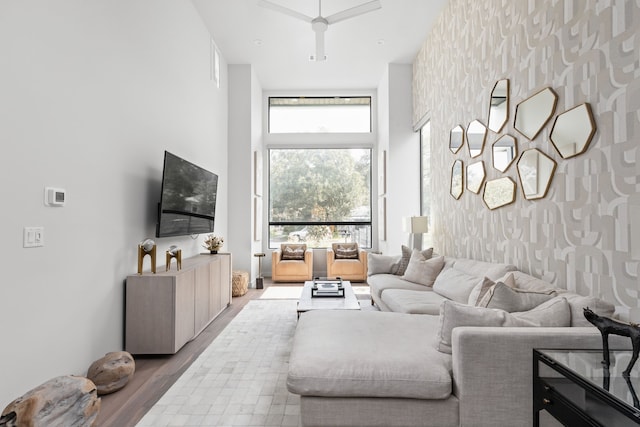 living room with a healthy amount of sunlight, ceiling fan, wood-type flooring, and a high ceiling