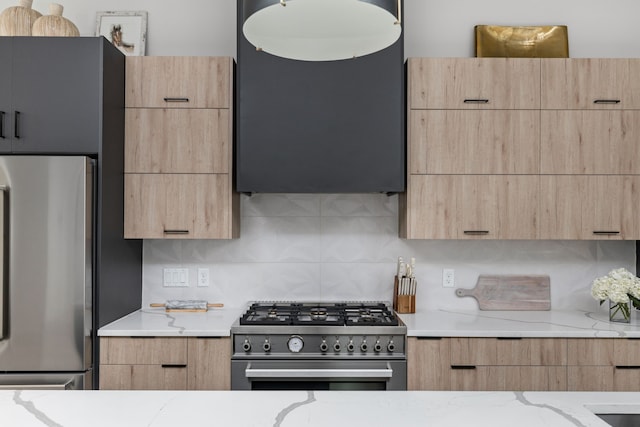 kitchen with light stone counters, stainless steel appliances, tasteful backsplash, and light brown cabinets