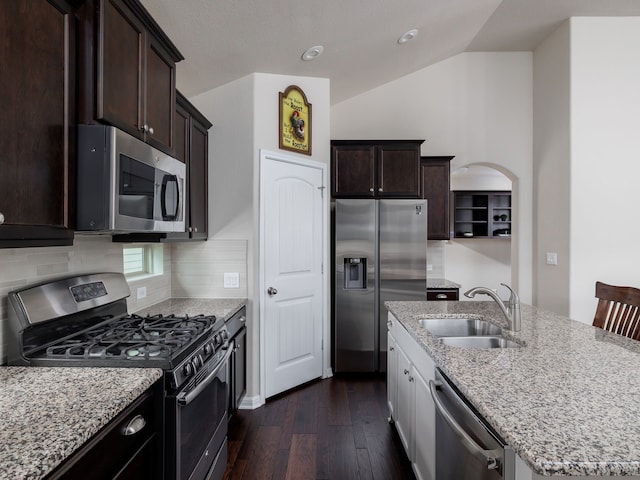 kitchen featuring stainless steel appliances, sink, vaulted ceiling, an island with sink, and decorative backsplash