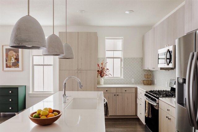 kitchen featuring light brown cabinets, pendant lighting, sink, decorative backsplash, and stainless steel appliances