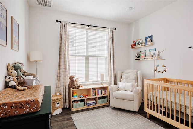 bedroom with a crib and dark hardwood / wood-style flooring