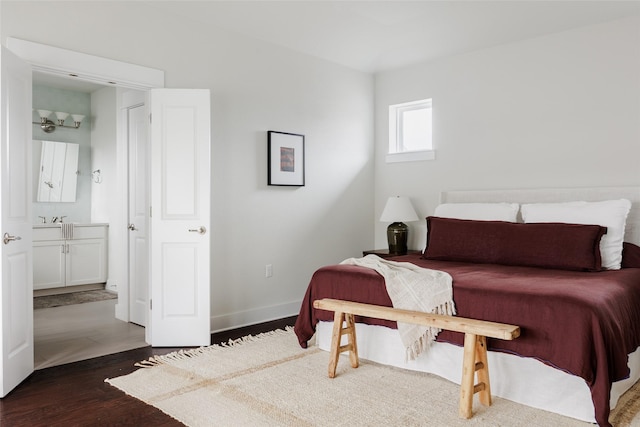 bedroom featuring ensuite bathroom, dark hardwood / wood-style flooring, and sink