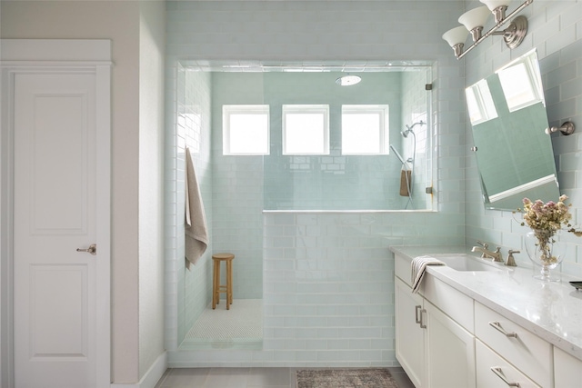 bathroom featuring tile walls, tile patterned flooring, a tile shower, and vanity