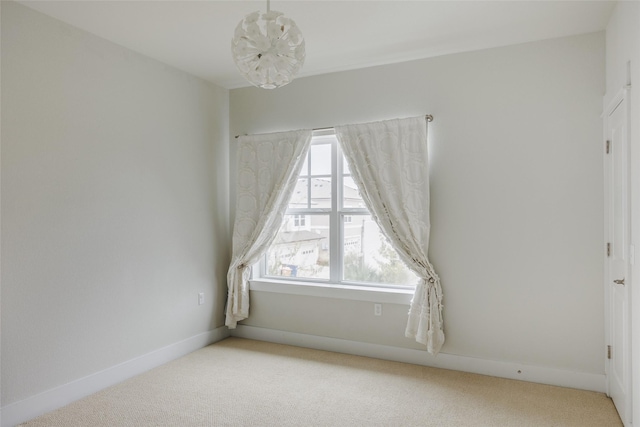 carpeted empty room featuring an inviting chandelier and a healthy amount of sunlight