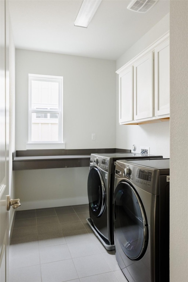 washroom featuring washing machine and dryer, light tile patterned flooring, and cabinets